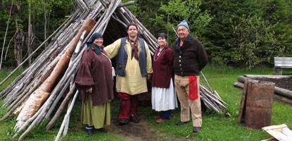 Staff in 18th century clothing stand near birchbark structure. Staff in 18th century clothing stand near birchbark structure.