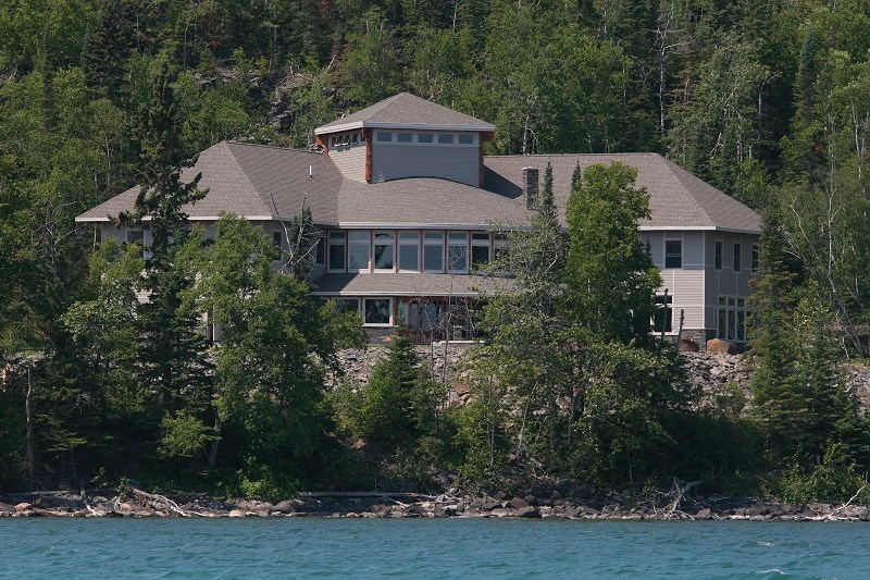 A building along a lakeshore surrounded by green trees.