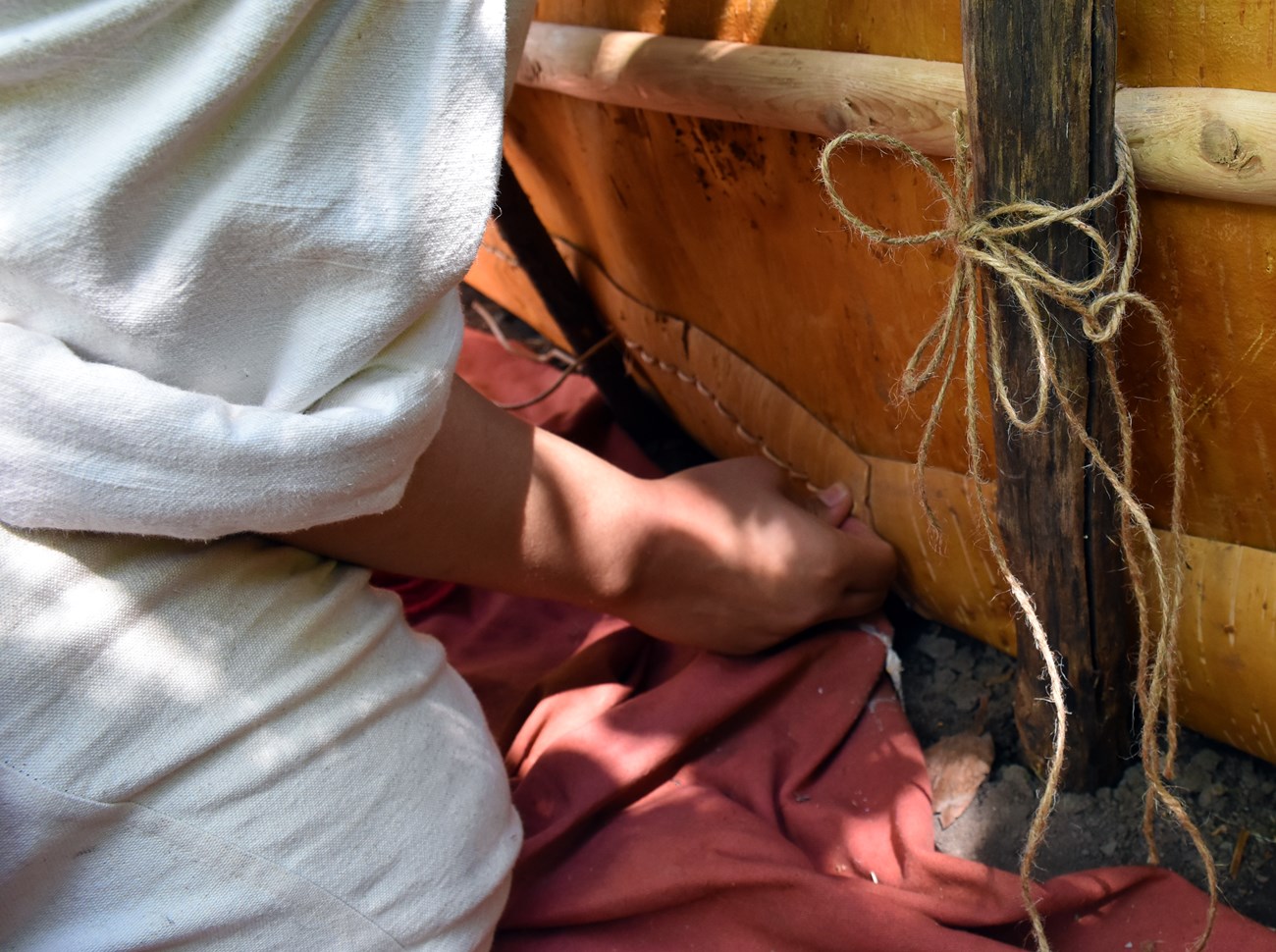 Sewing detail Detail of hands with spruce root along a bark canoe side.
