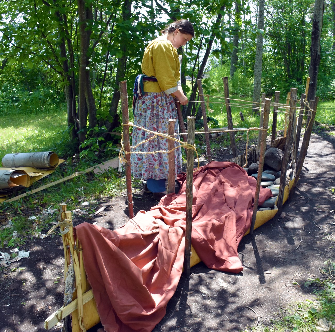 Staking the canoe sides A reenactor places stakes to form the sides of a canoe.