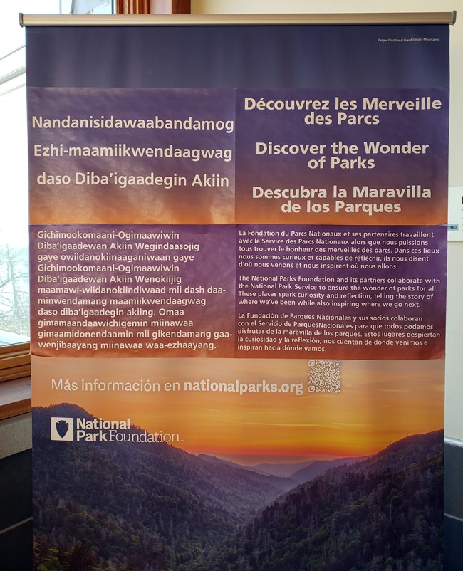 Banner showing a sunset behind mountains with text in several languages.