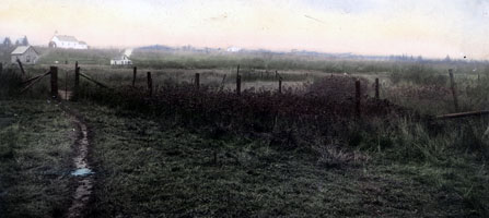 An old photograph of the Grand Portage Trail passing by an overgrown fence in the meadow area.