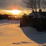 Sunrise over the Grand Portage historic depot. Sunrise over water with log structures in the foreground.