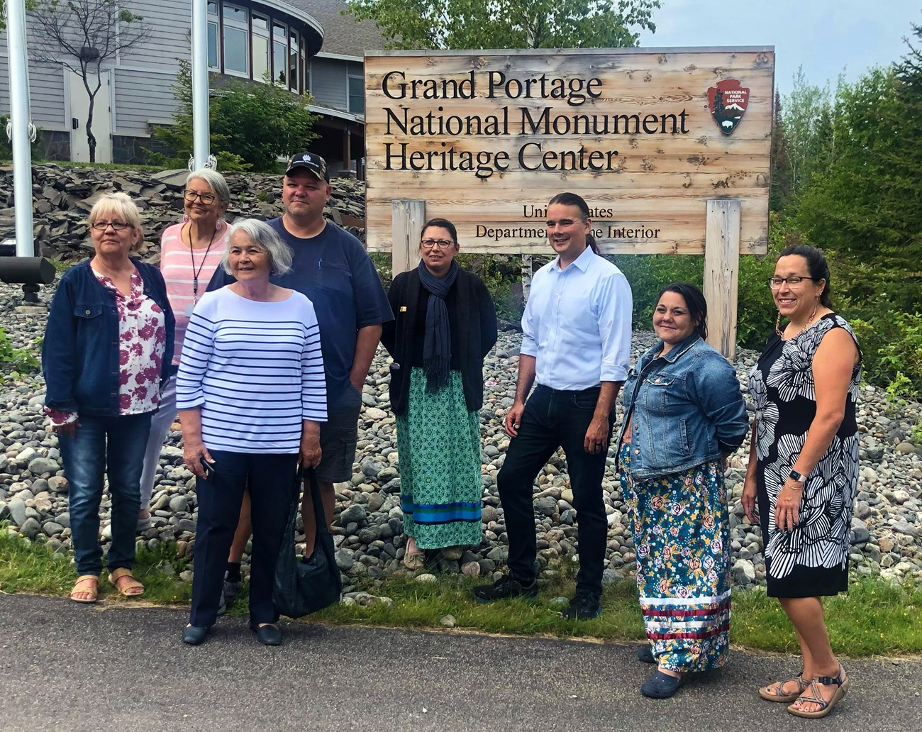 Eight people standing in front of the NPS Grand Portage National Monument sign.