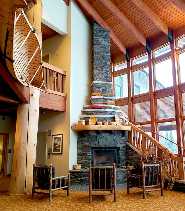 A stone fireplace. Hung above to the left is a bark canoe.