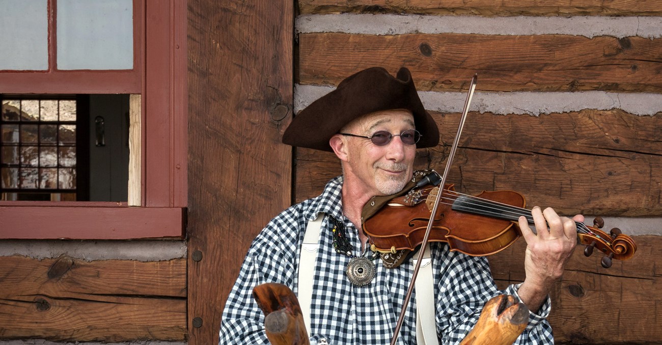 A person wearing a tricorn hat, holding a fiddle.