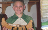 Grand Portage mentorship intern proudly displays the birchbark  model he made.