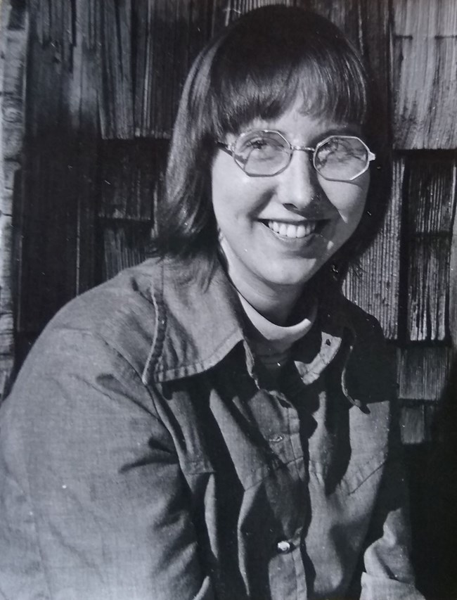 Woman smiling into the camera with bookshelf in the background