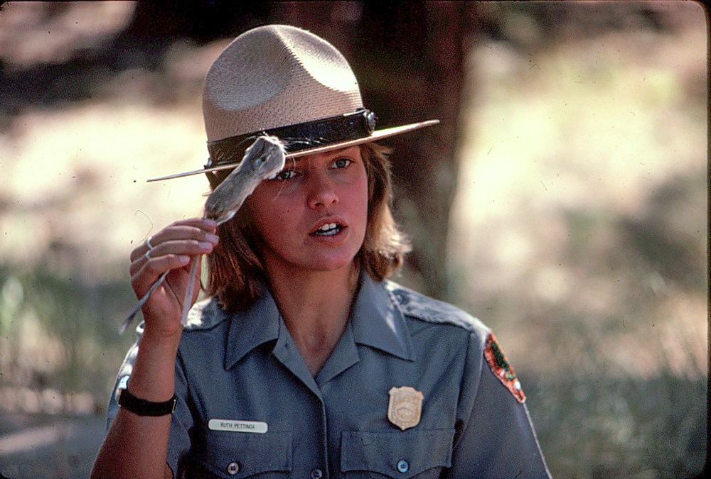 1970s photo of a female ranger speaking and holding a taxidermy kangaroo rat