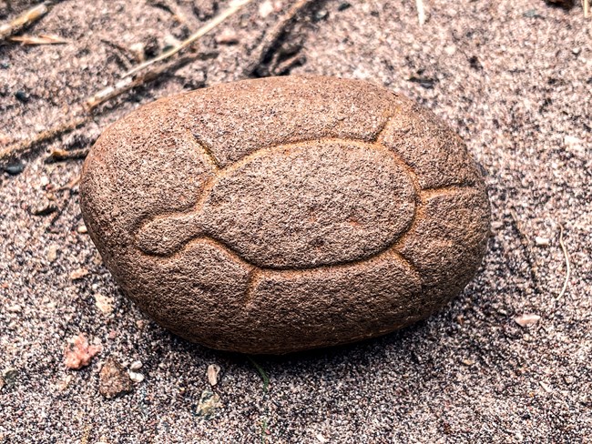 A simple petroglyph of a turtle incised onto an oval rock