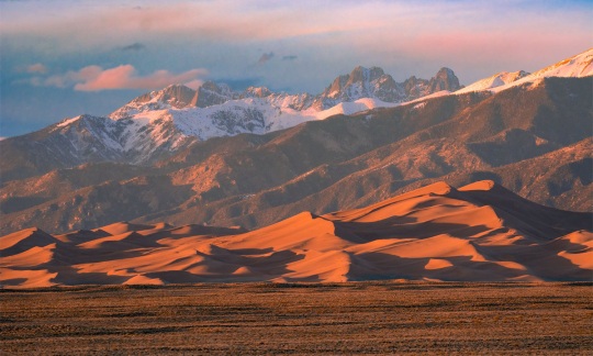 Warm late afternoon colors illuminate the dunes below the Sangre de Cristo Mountains