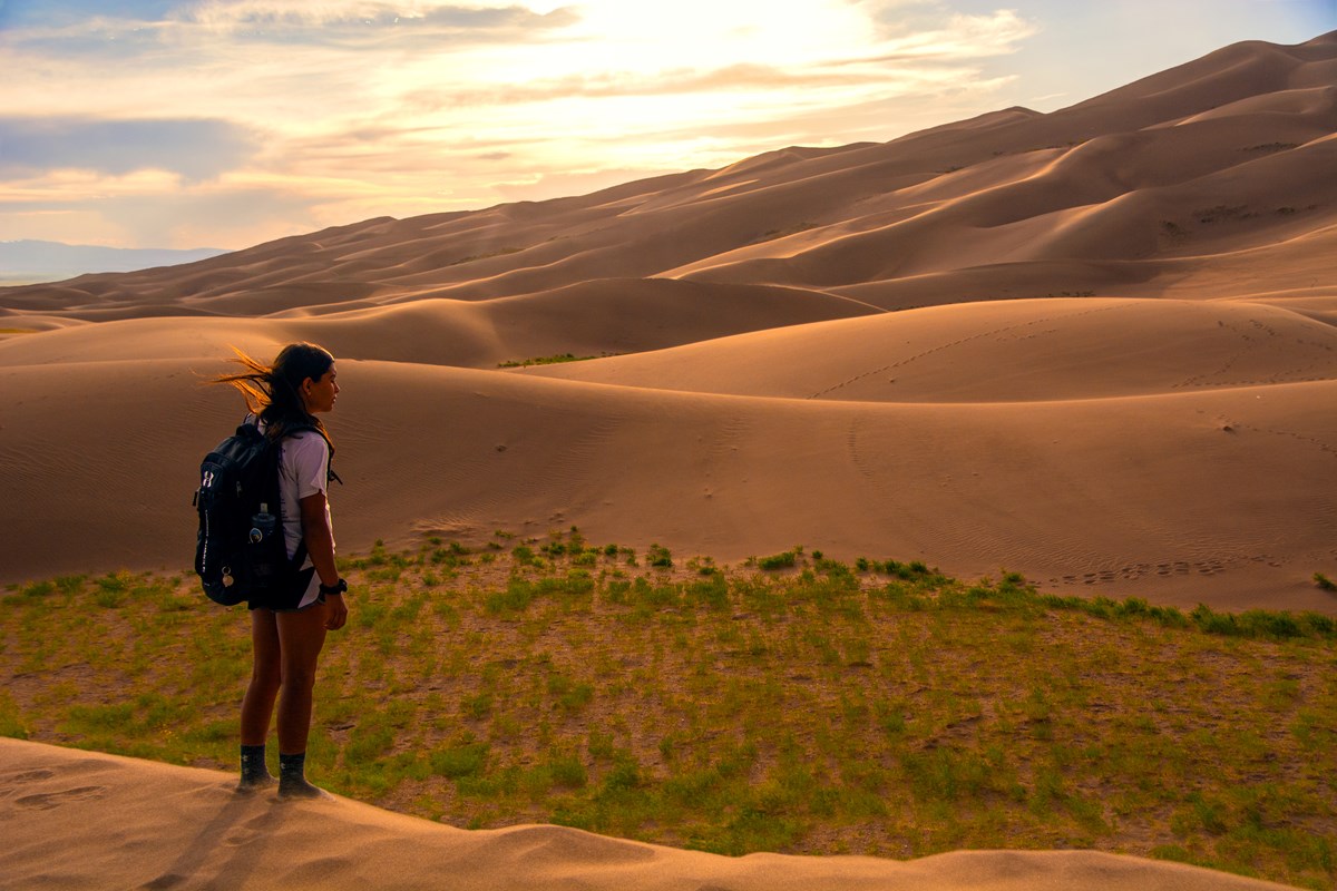 Woman standing on dunes wearing a backpack