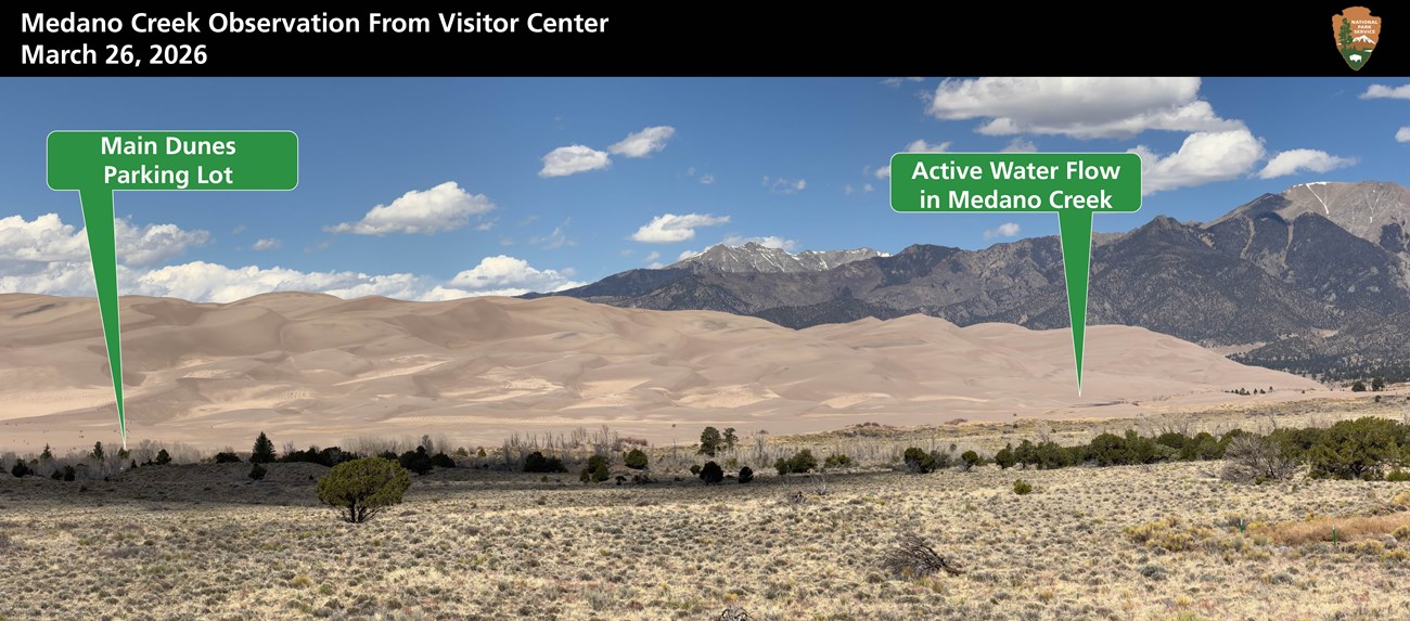 Sand Dunes and Montains with green arrows pointing to where the main dunes lot is located, and where Medano Creek is flowing on March 26 2026