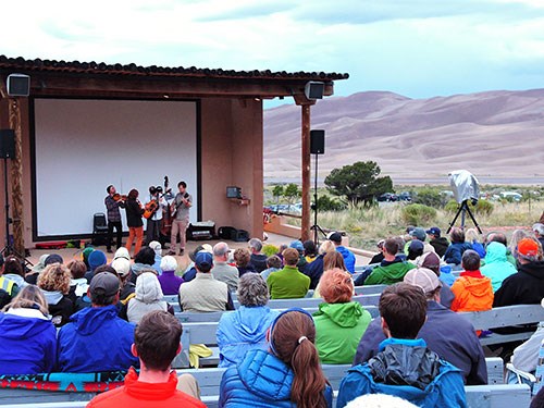 A view of the park amphitheater with a small band on stage and the dunes in the background
