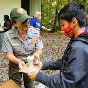 Student and Ranger looking at a piece of pottery made by the student.