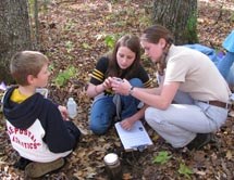 Ranger and two students use tools to test soil.