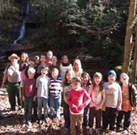 Students standing together after a hike with a waterfall in the background.