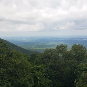 Mountains with forest, town and clouds in background.