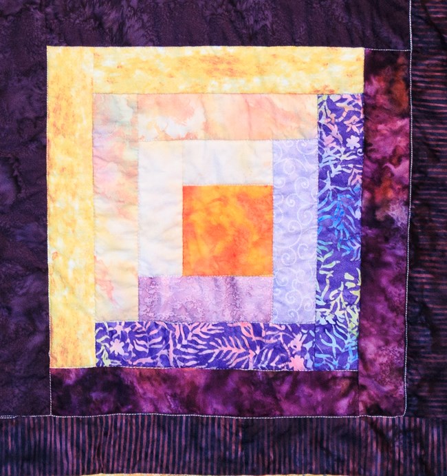 a Log Cabin quilt block made up of purples.
