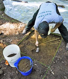 Heath Bailey carefully scrapes away soil layers in an excavation unit.