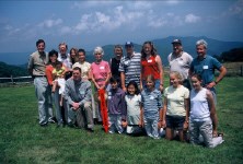 Group of people standing on grass with mountains behind them.