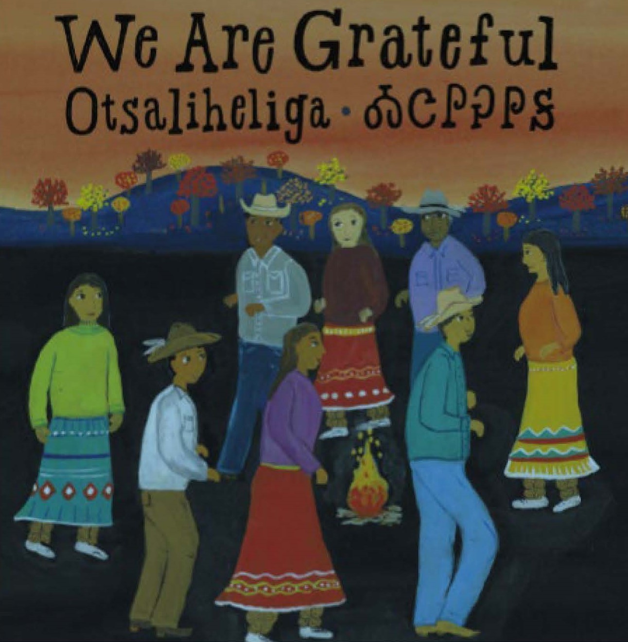 The cover of a book titled "We Are Grateful Otsaliheliga". Cover art includes multiple people walking around a fire with mountains and trees during autumn in the distance.