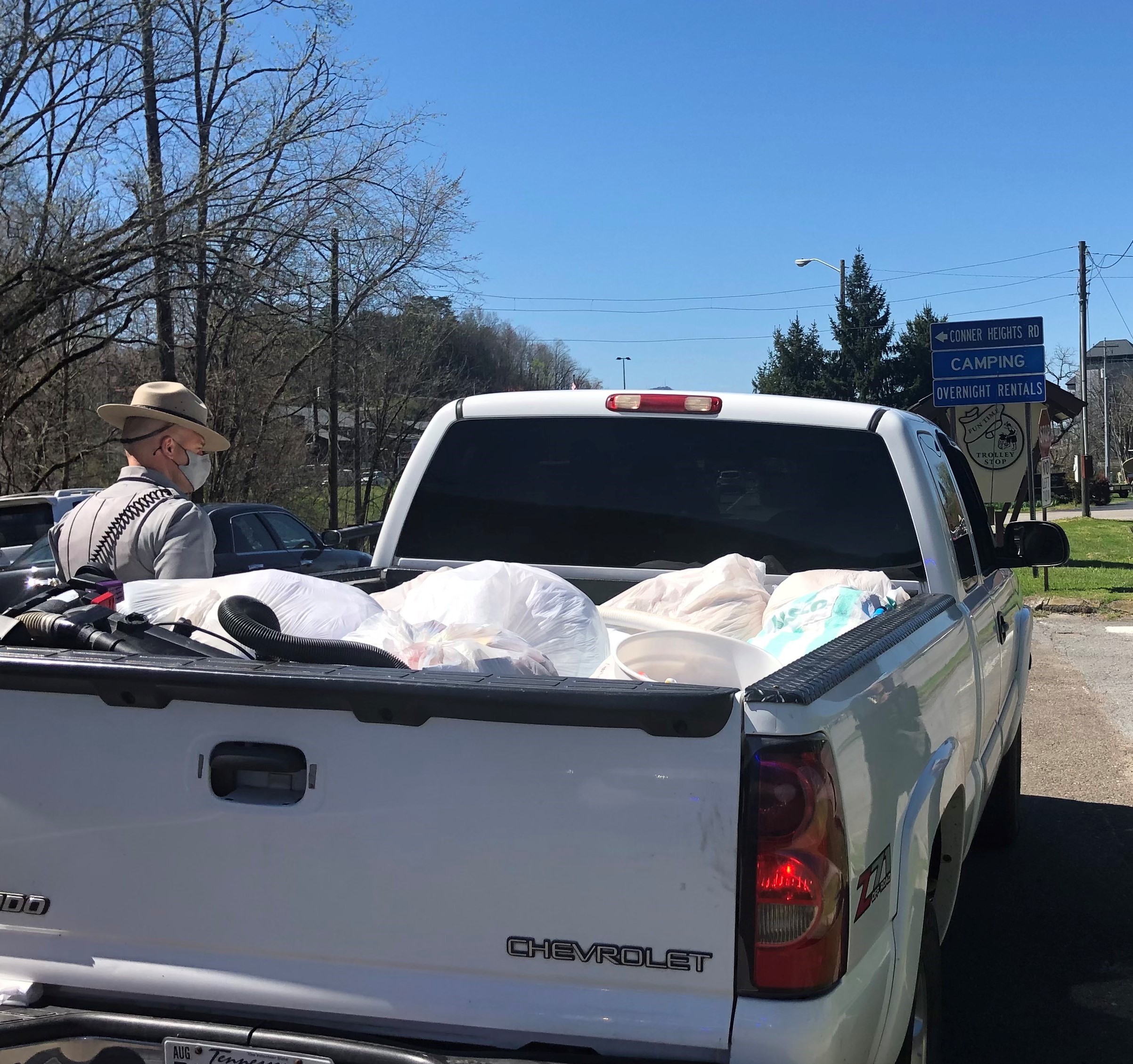 Ranger speaking with driver of white truck with unsecured trash in the bed.