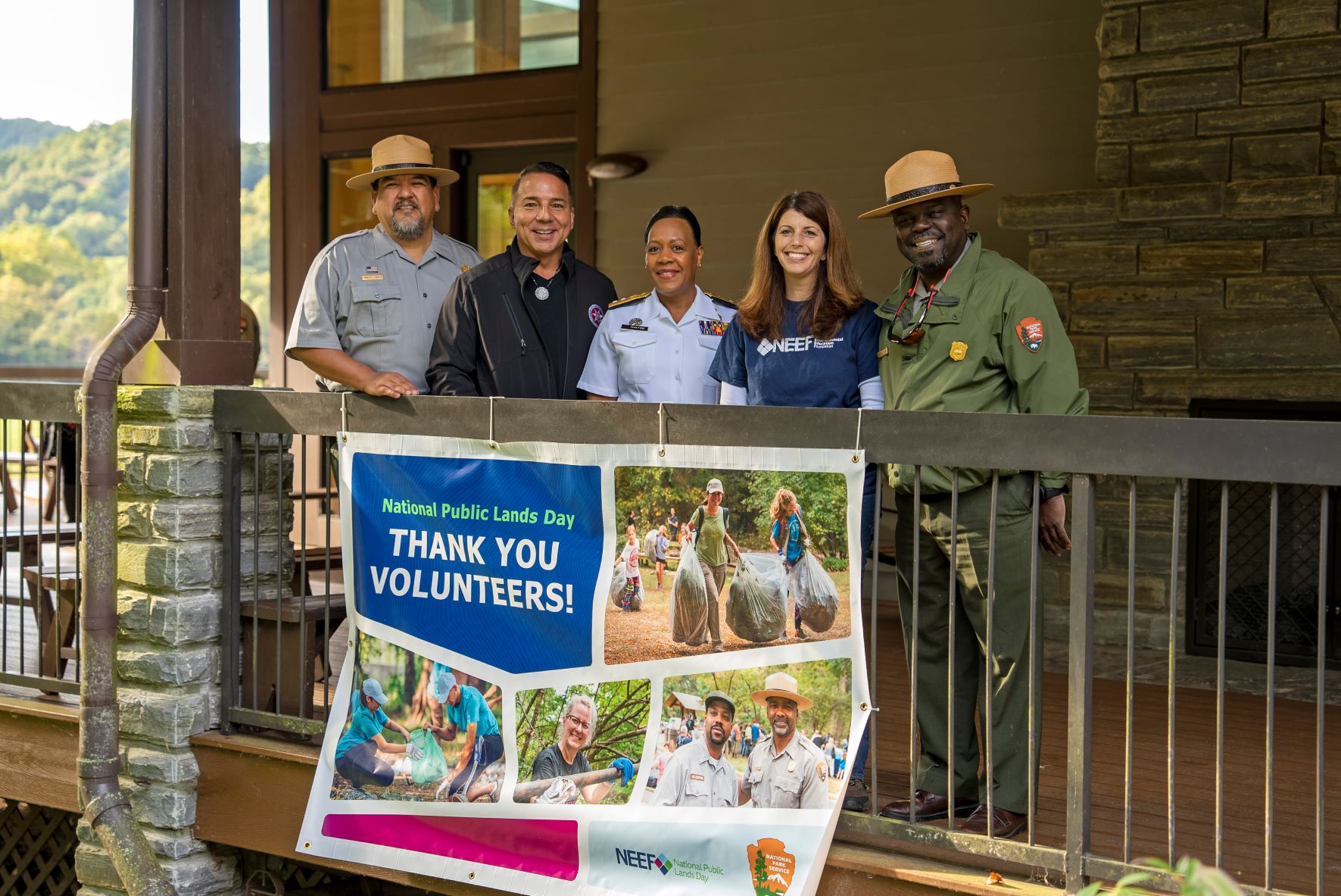 2022.9.24 Director Sams, Chief Sneed, Rear Admiral Hinton, NEEF CEO Deoudes, Sup Cash on NPLD A group of five people standing on a porch behind a sign that reads "National Public Lands Day, Thank You Volunteers!"