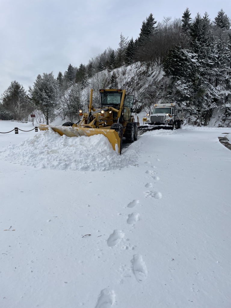 snow plow moving snow with mountains in the background