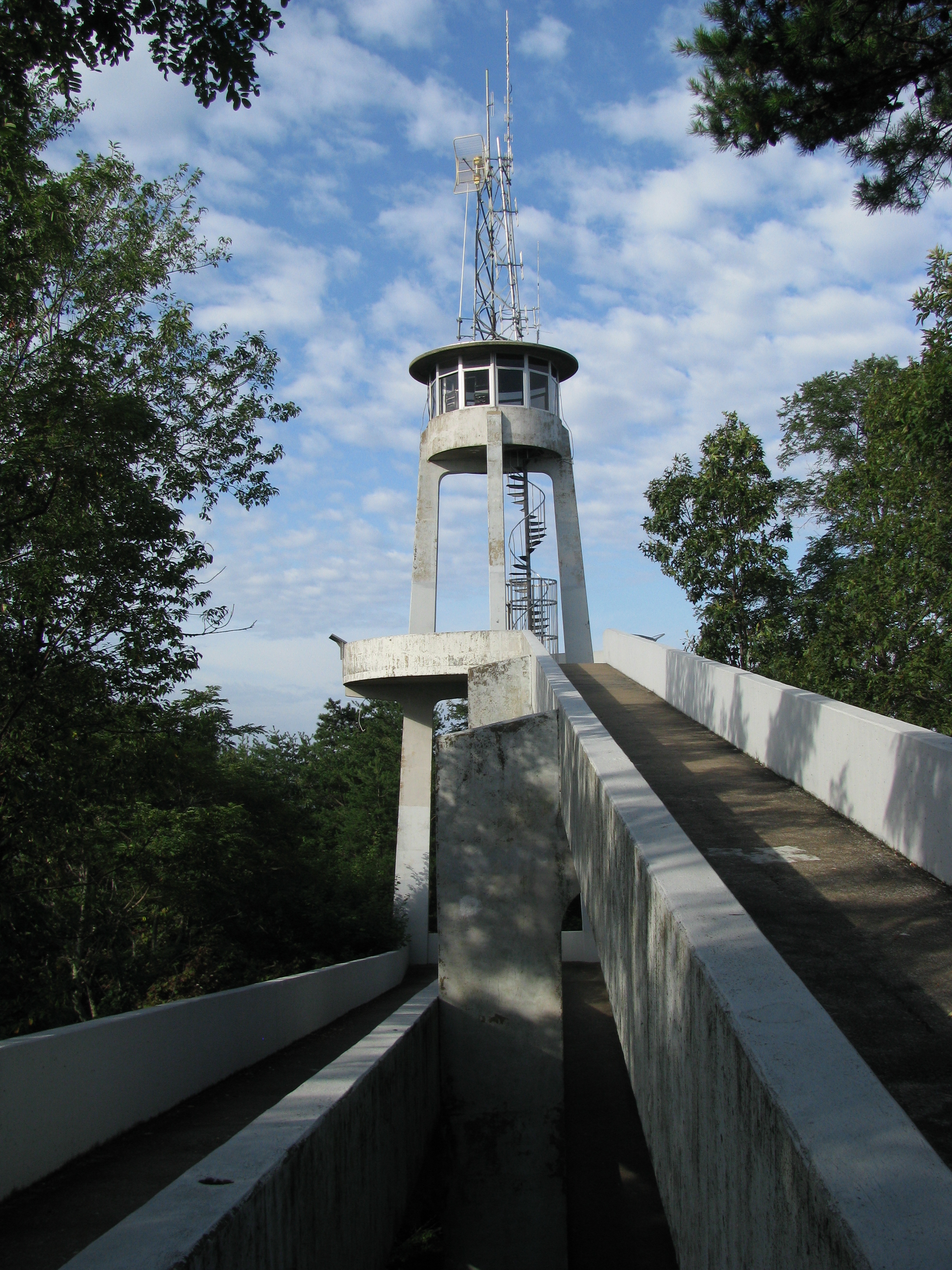 Look Rock Tower A tower with radio equipment on top of it and a paved path leading up to it. Green trees are seen on either side and a partly cloudy sky is in the background.