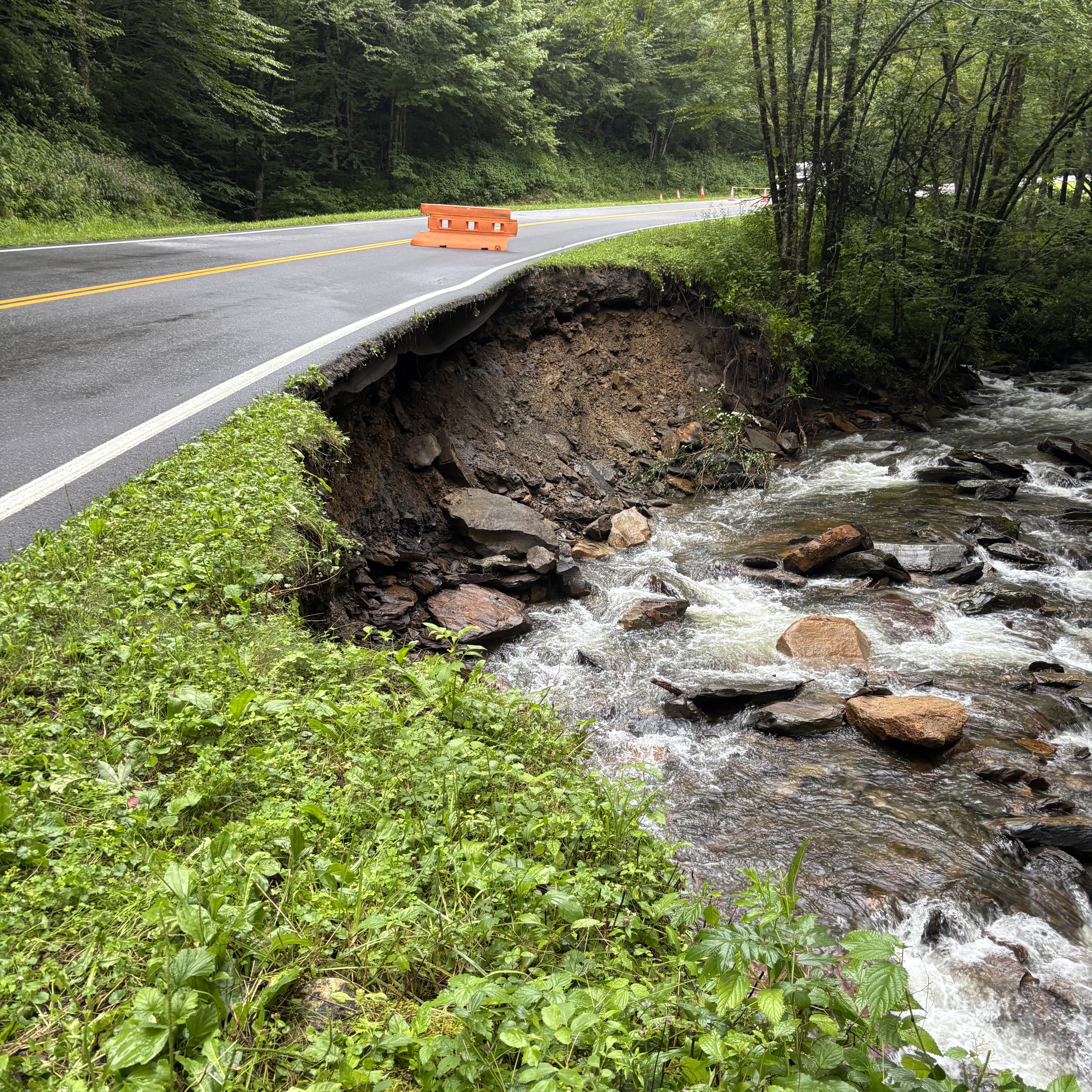 A road that has a washout underneath of it.