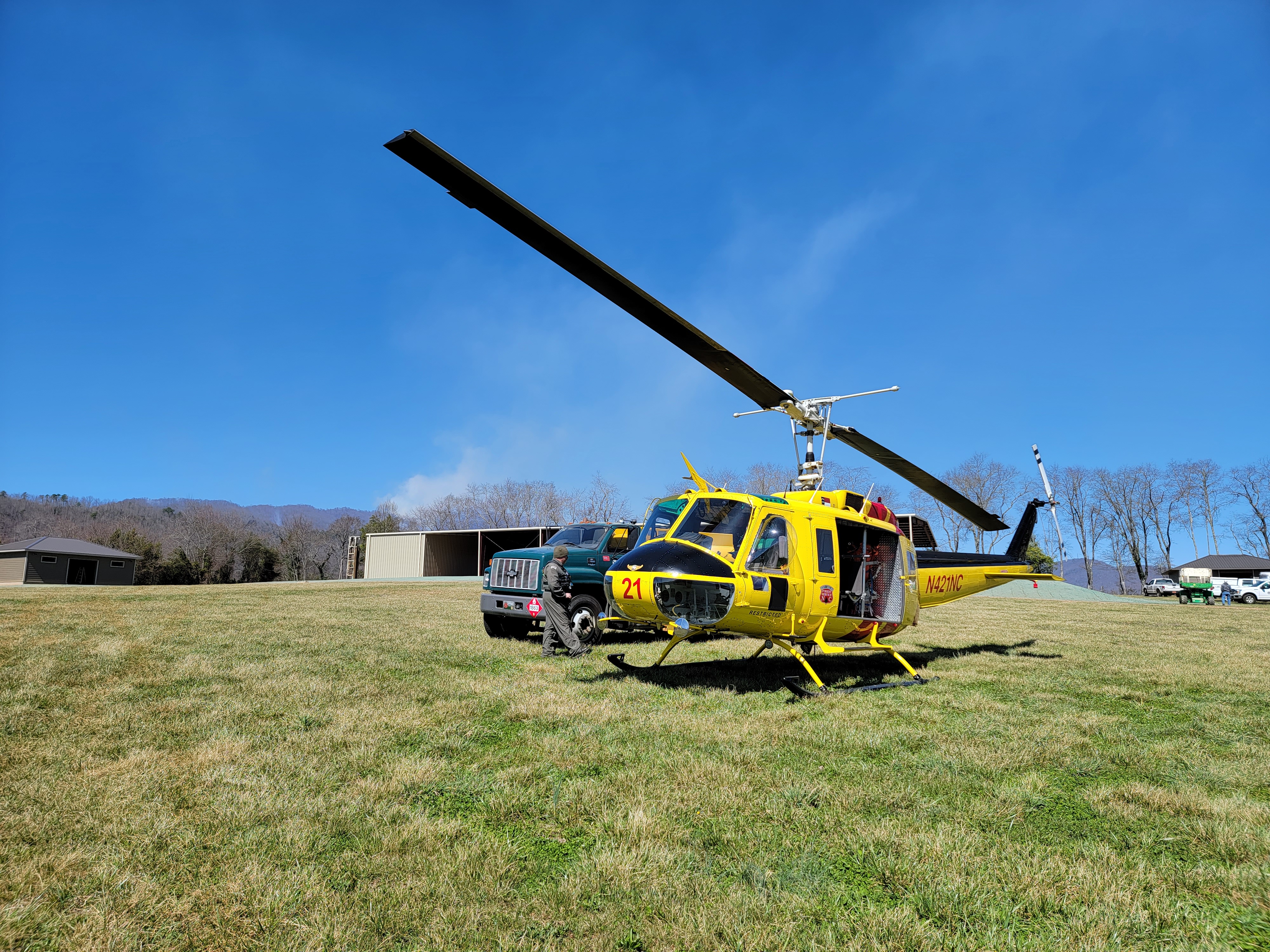 Yellow helicopter in field preparing for take off