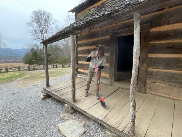 person sweeping porch of log cabin person sweeping the porch of a historic log cabin