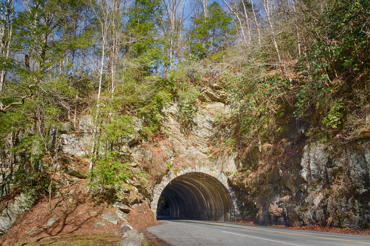 A short tunnel on a mountain road with no cars going by on a sunny day.