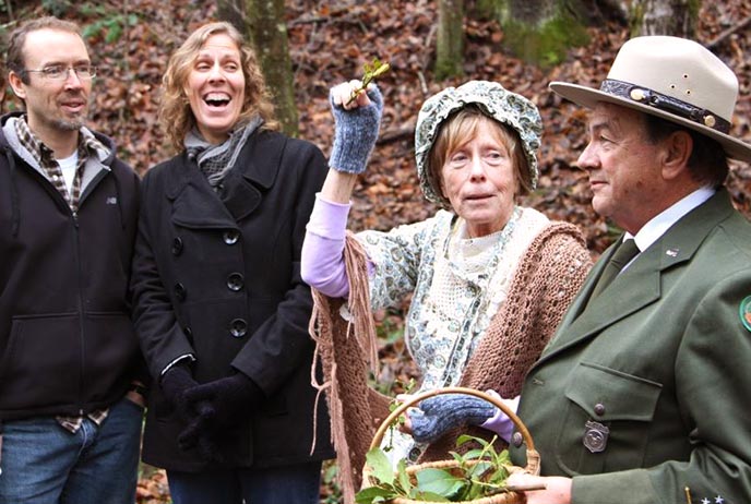 A man and a woman in period costumes from the early 1900s speak to two visitors.