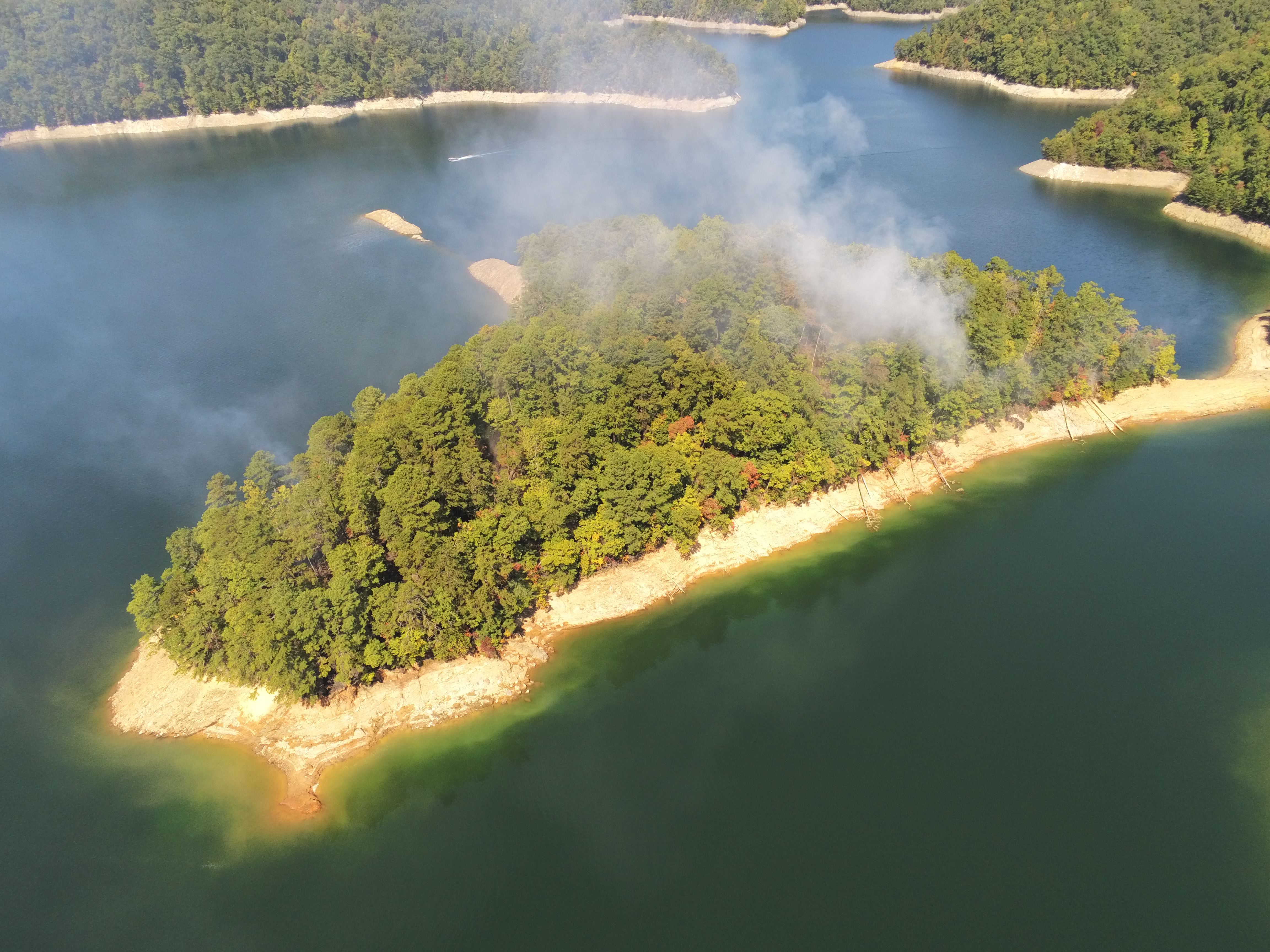 Lake Fire aerial Sept. 27 smoke appearing from thick green trees is visible from a small island in a lake