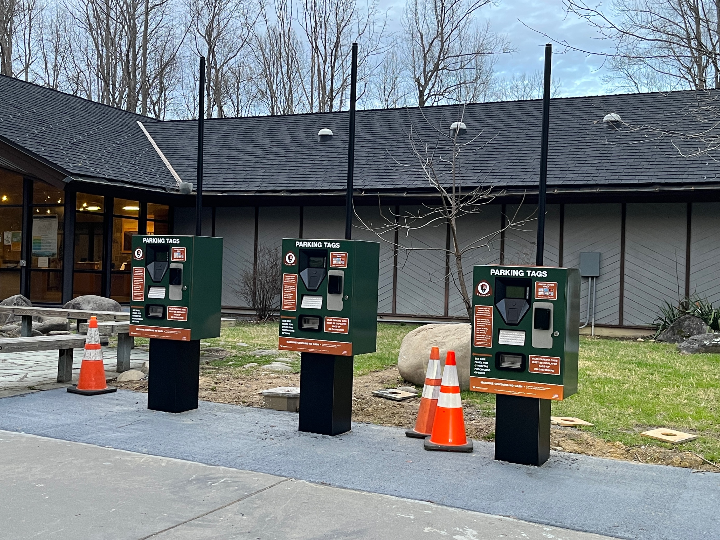 three green, black and brown automated fee machines in front of building