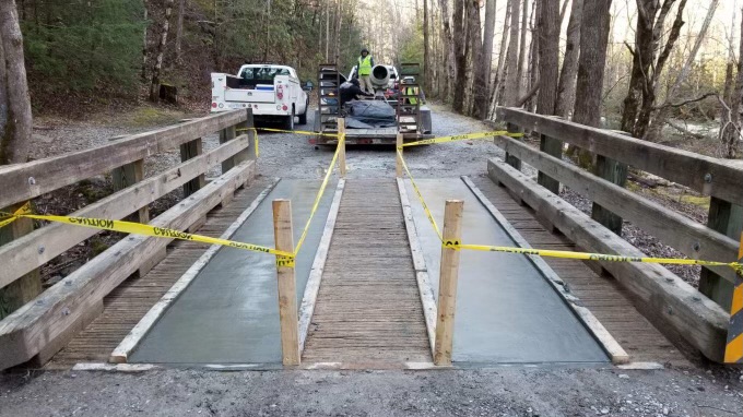 Small vehicle bridge with wooden railings, wooden decking and new leveling concrete
