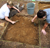 Archeologists carefully scrape away layers from a proposed building site.
