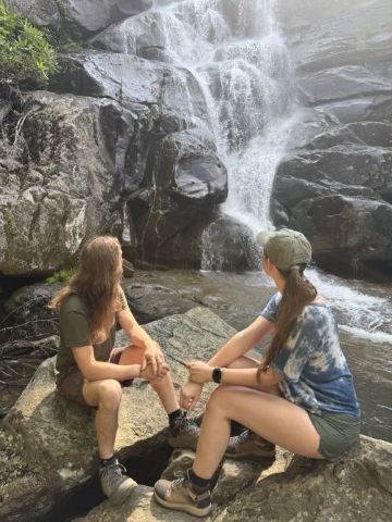 visitors looking at a large waterfall from some rocks.