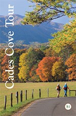 The cover of the Cades Cove auto tour booklet. White text says "Cades Cove Tour" with an image behind the text of two people walking on a paved road beside a fence. Trees showing fall colors are in the background.