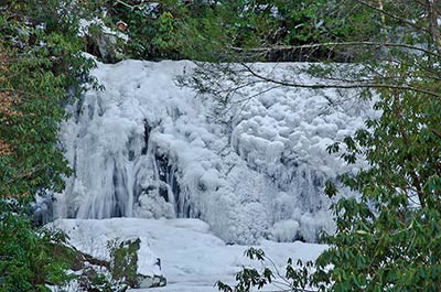 Heavy ice coats the face of a waterfall.