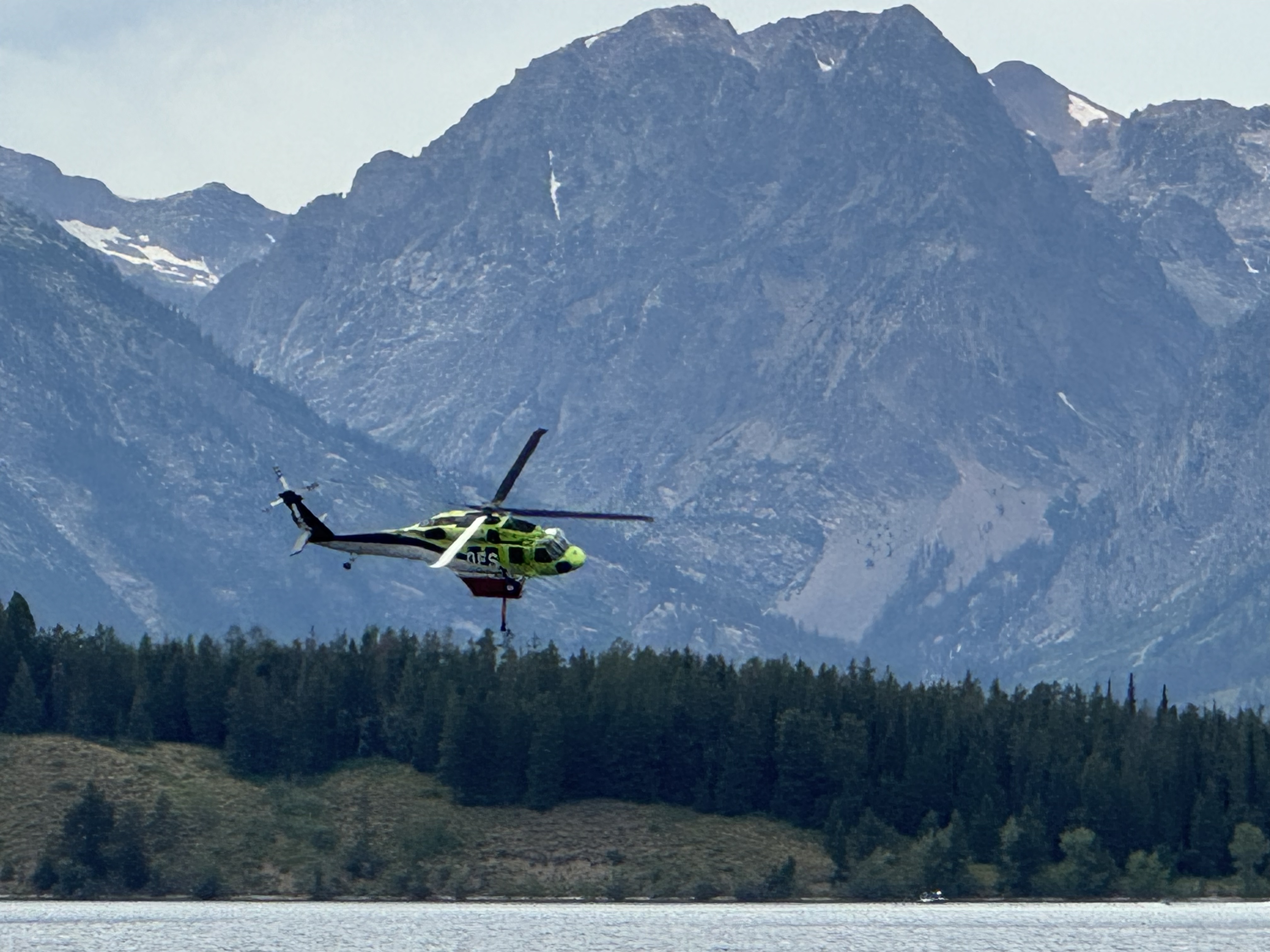 Signal Flats Fire helicopter over Jackson Lake helicopter flying over a lake with mountains in the background
