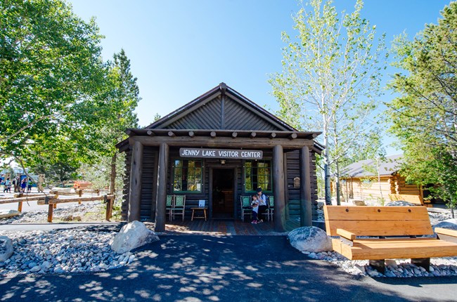A log cabin that houses the Jenny Lake Visitor Center on a sunny day.