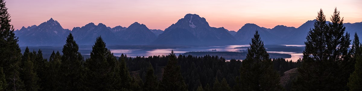 Teton Range in shadows with Jackson Lake below at sunset with a rose to purple sky
