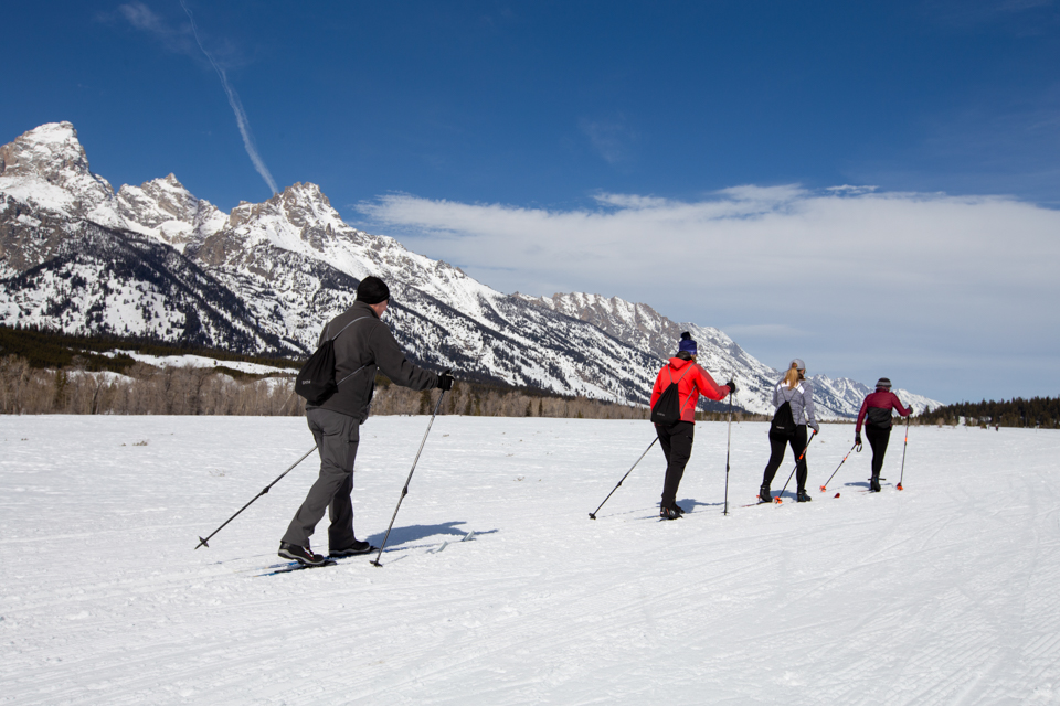 Cross-country skiers enjoying the Teton Park Road with the Teton Range in the background and a snow-covered landscape
