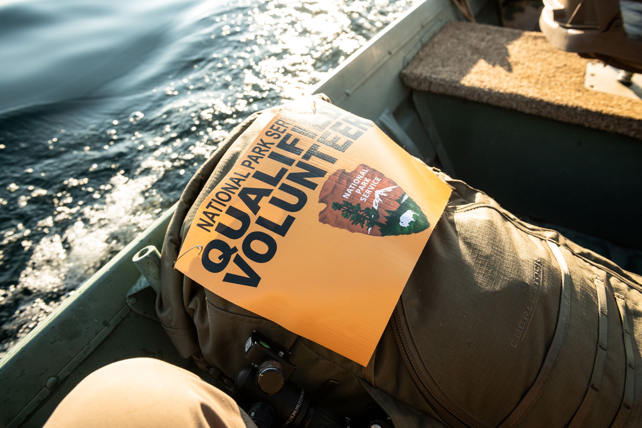 an orange sign reading "qualified volunteer" on a tan backpack in a boat
