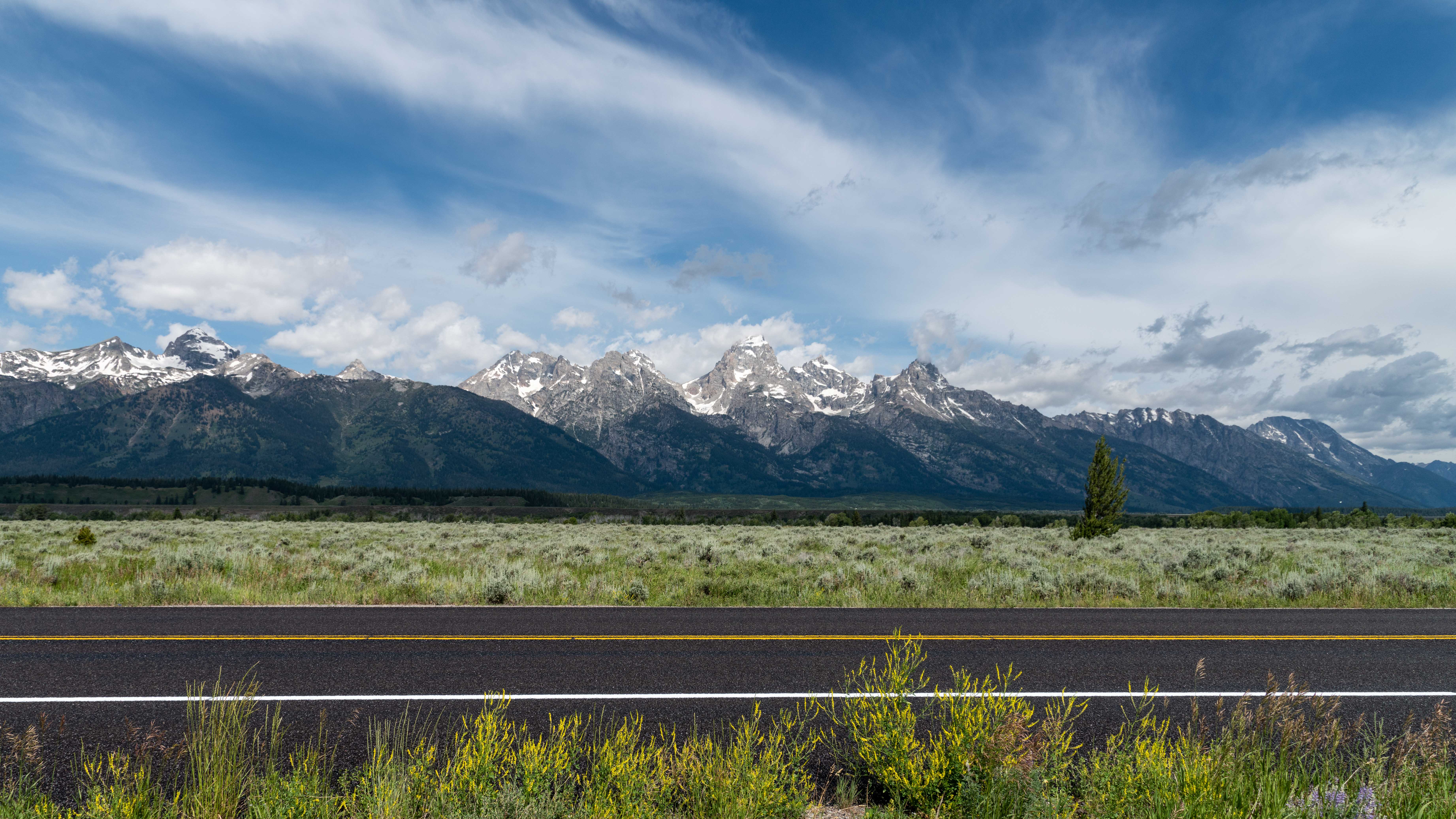 Freshly fog sealed roadway along U.S. Highway 89 with the Teton Range in the background.