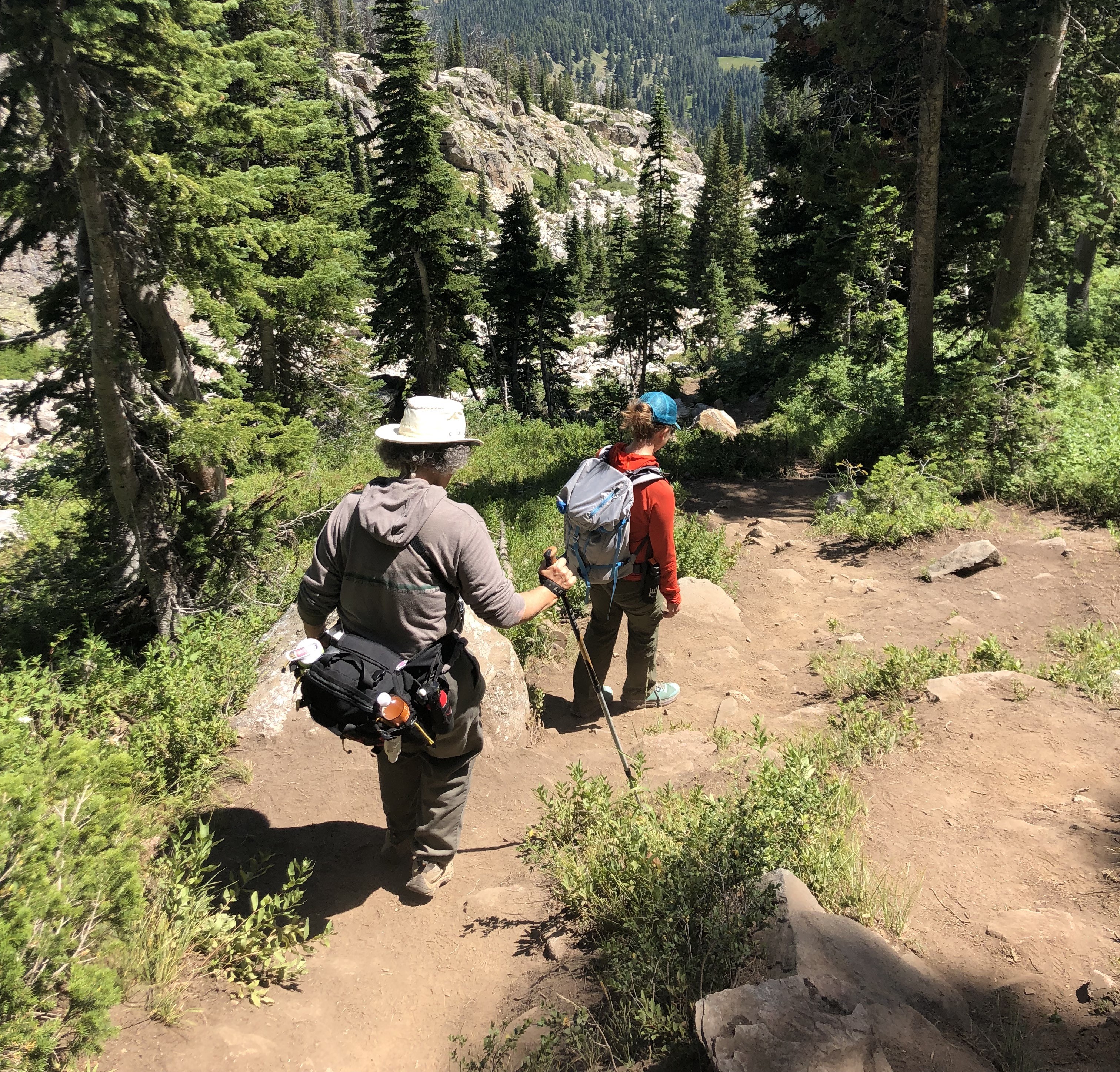 Two hikers on steep terrain descending from Delta Lake.