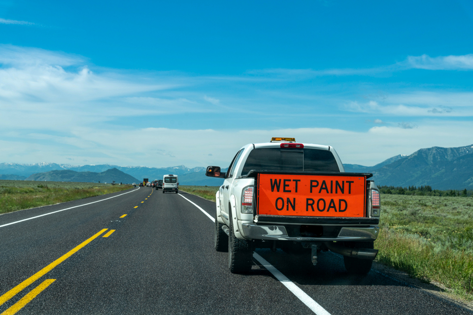 Road Striping Truck with "Wet paint on road" sign along highway in Grand Teton National Park